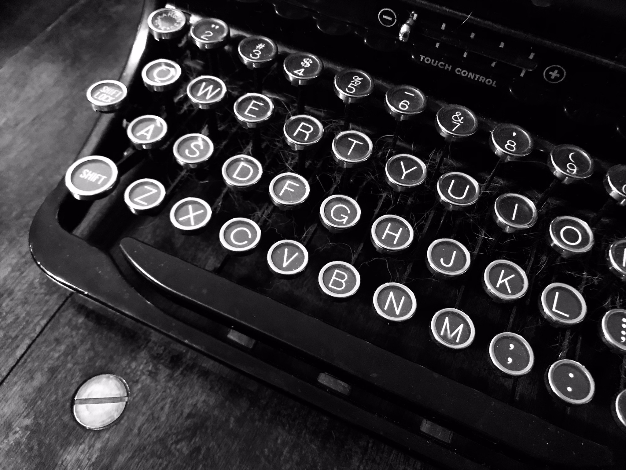 A close up of a black typewriter sitting atop a wooden desk